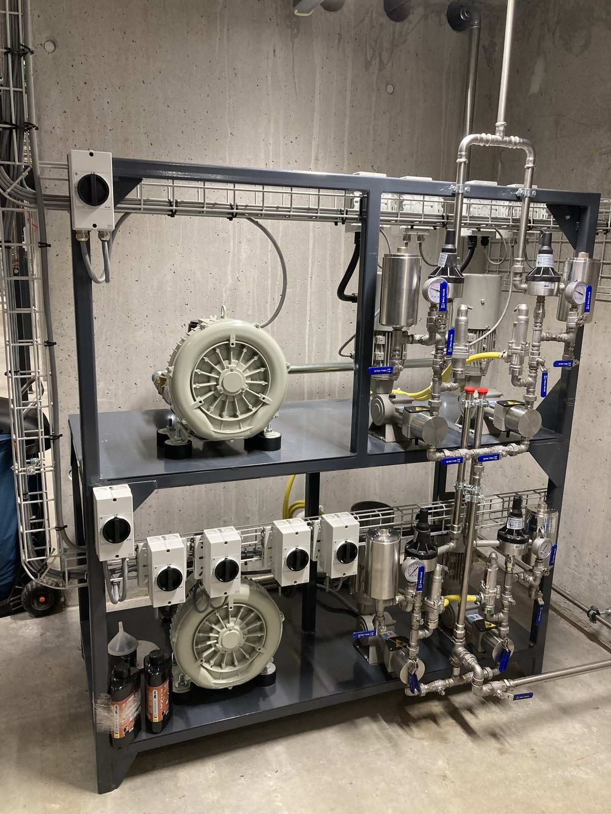 Impianto SNCR Ecotherm installato — skid di controllo con pompe, valvole e quadro PLC, in un cantiere con pareti in calcestruzzo e passerelle portacavi